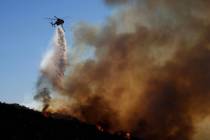 Water is dropped by helicopter onto the Franklin Fire, Tuesday, Dec. 10, 2024, in Malibu, Calif ...