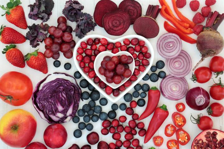 Purple and red health food with fresh fruit and vegetables in heart shaped porcelain dishes and ...