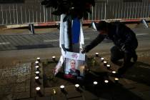 A man lights candles and displays photos of what Hamas says are four dead Israeli hostages hand ...