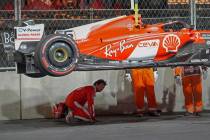 Ferrari driver Carlos Sainz, of Spain, looks at the bottom of his car after running over a manh ...