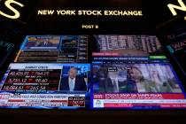 Financial news is displayed as people work on the floor at the New York Stock Exchange in New Y ...