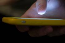 A man uses a cell phone in New Orleans on Aug. 11, 2019. (AP Photo/Jenny Kane, File)